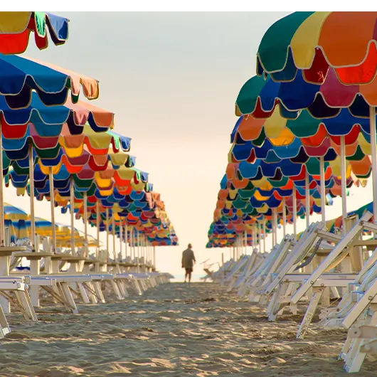 A scenic view of Rows of multi colored beach umbrellas during sunrise A scenic view of Rows of multi colored beach umbrellas during sunrise