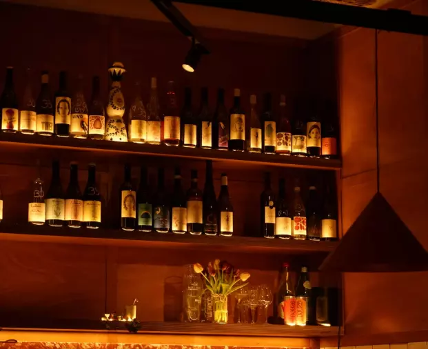 wine bottles lined up on shelves in low lit wine bar in Nice, france
