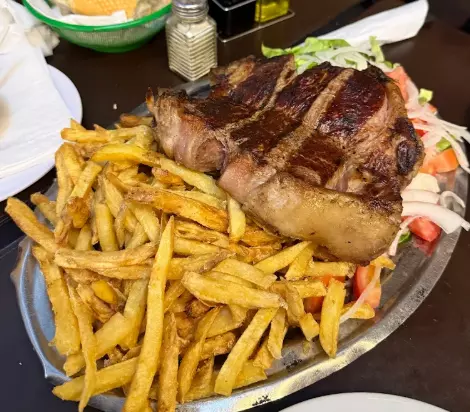 Thick cut of steak with fries and salad at Desnivel parrilla, Buenos Aires
