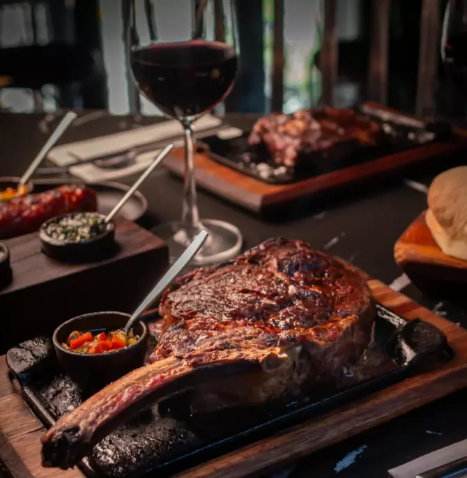 Large ribeye on hot plate with a glass of wine at Hierro, Buenos Aires