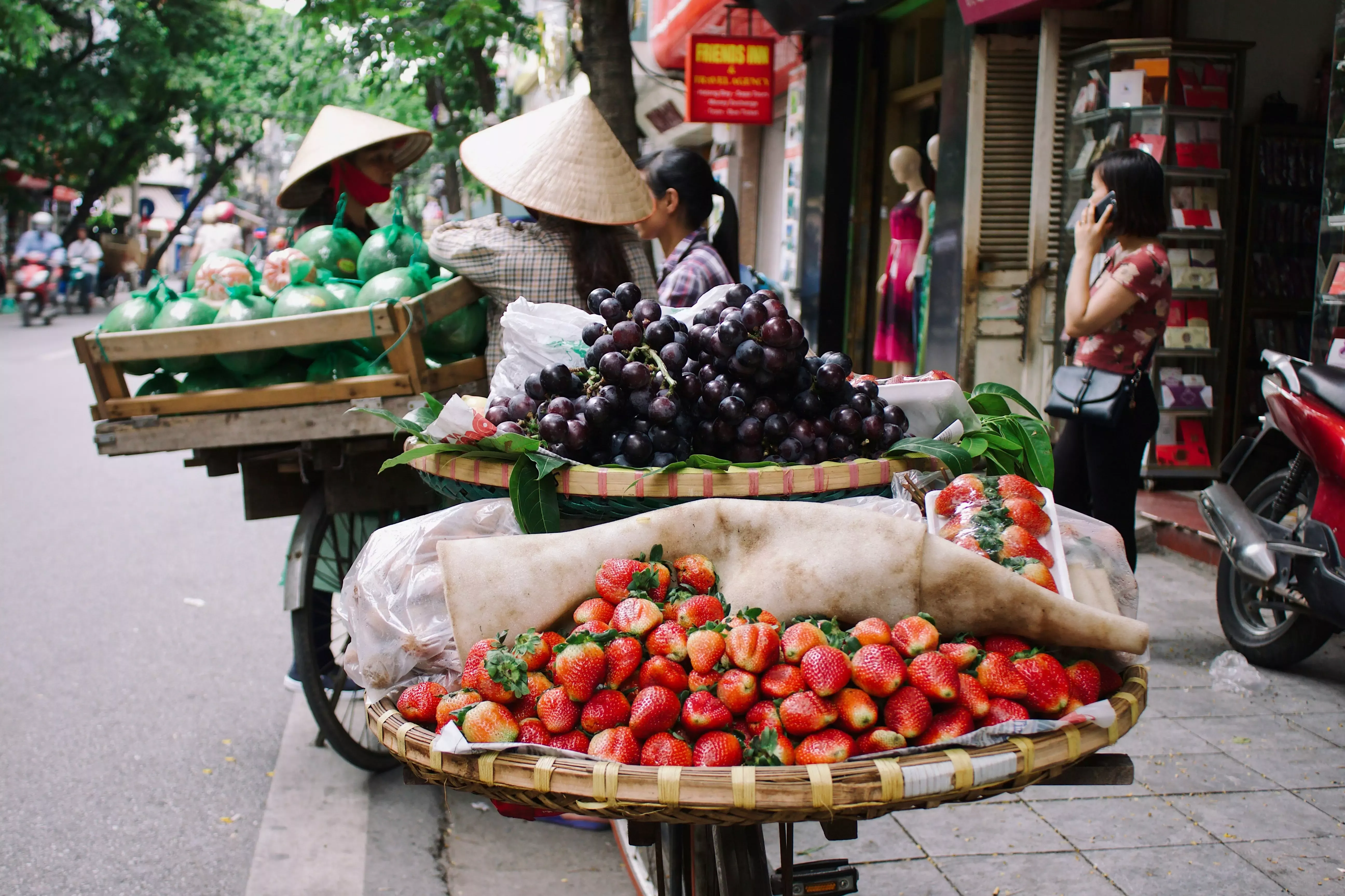 Vietnamese market traders in traditional clothing getting ready to sell fresh fruits at the market.