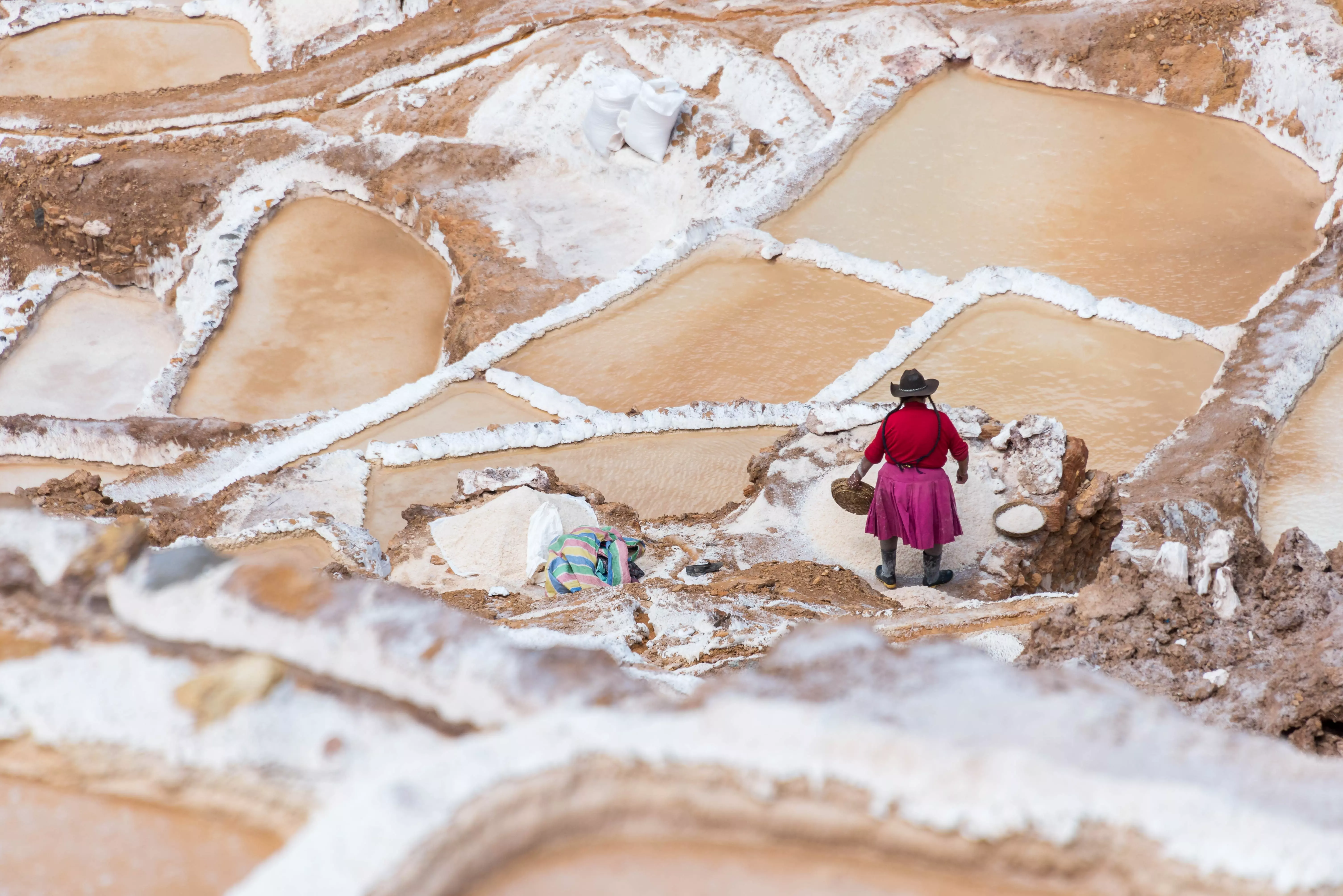 Woman in traditional indigenous Peruvian dress working in the Maras Salt Mines