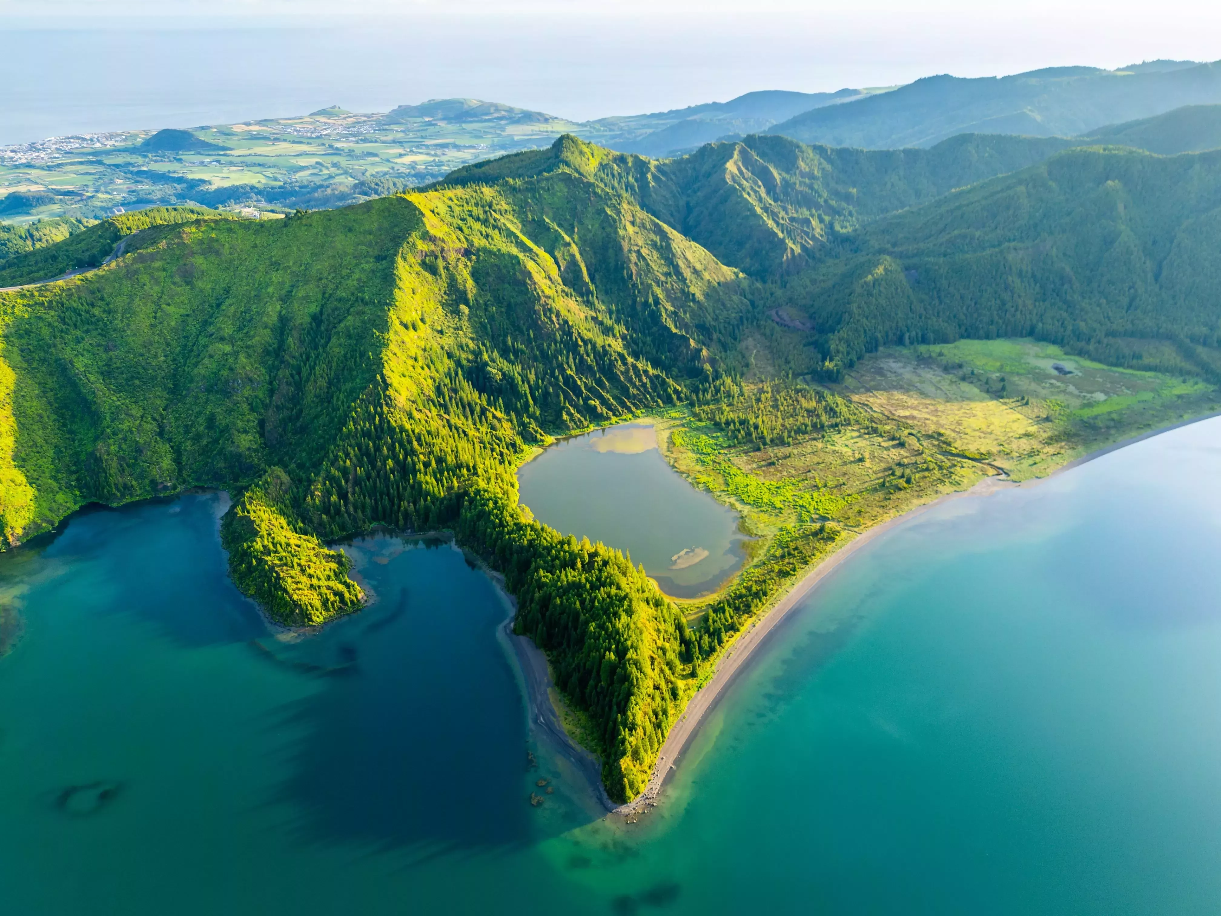 Aerial view of volcanic lake surrounded by lush green hills in the Azores