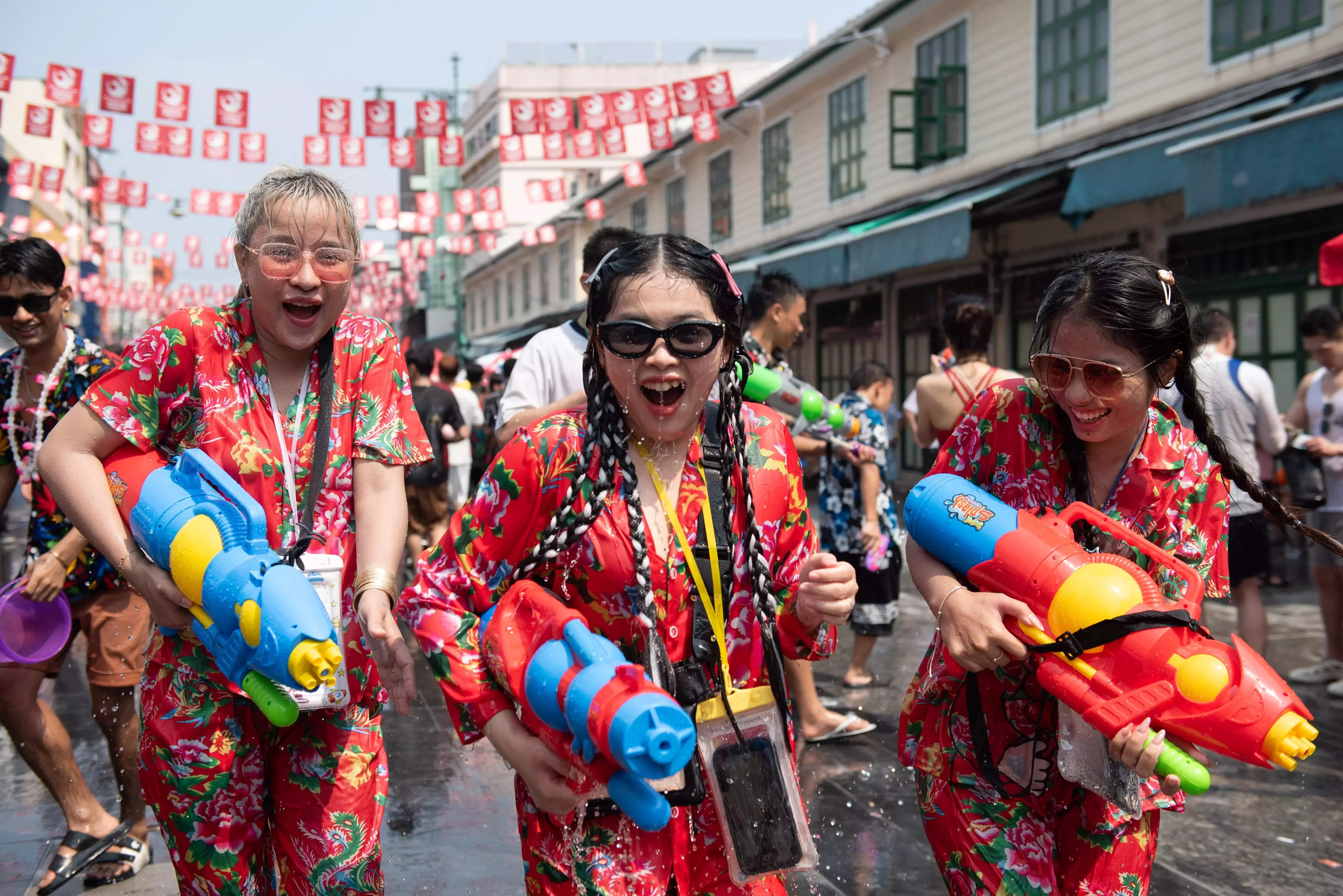 Three girls smile and hold water guns playfully during Songkran, Thailand