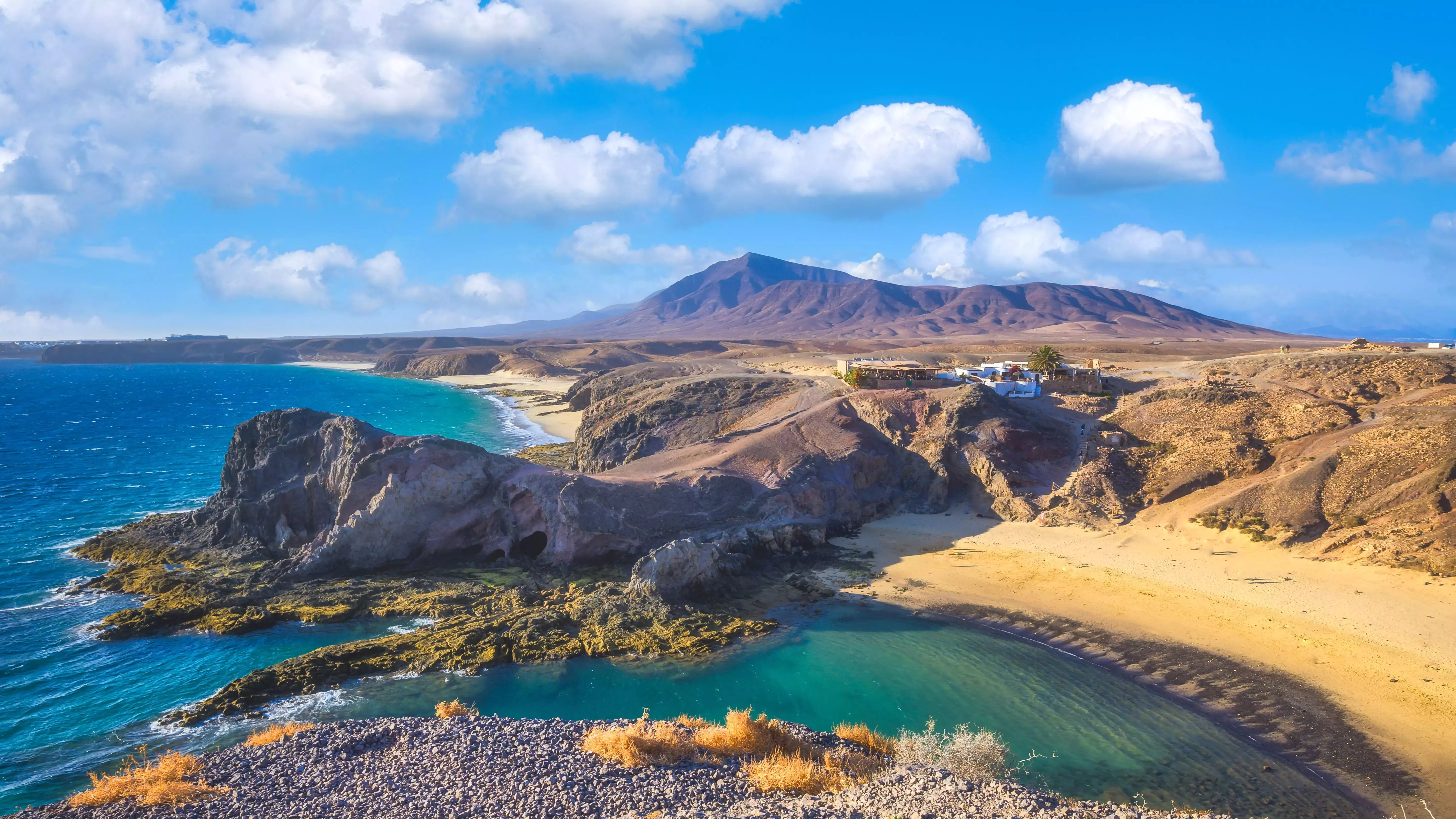 View of golden beach and blue Atlantic Ocean backed by hills on Lanzarote, Canary Islands