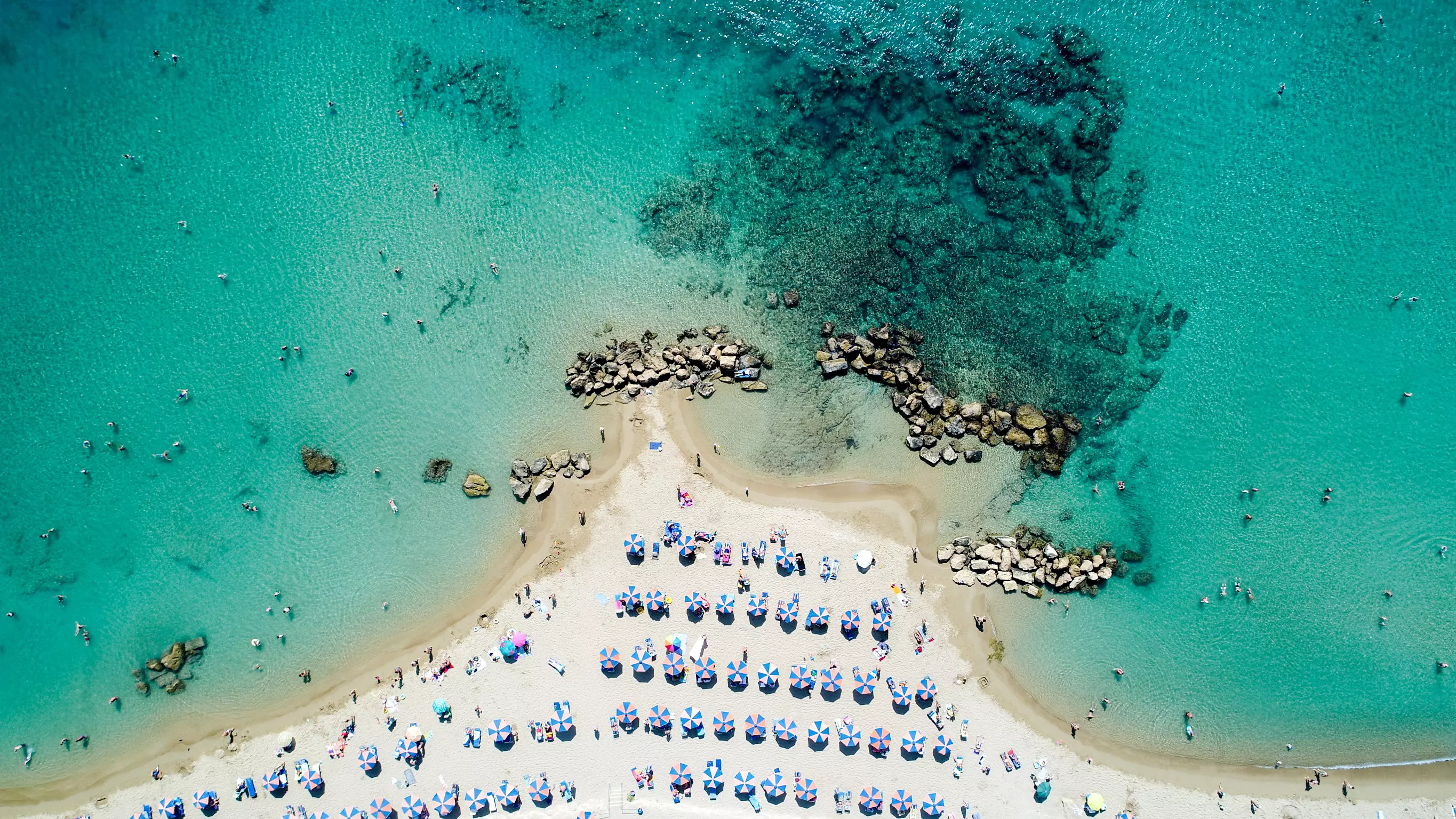 Drone view of white sand Cyprus beach dotted with sun loungers
