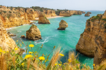 Aerial shot of golden rock formations in the light blue seas of the Algarve, Portugal